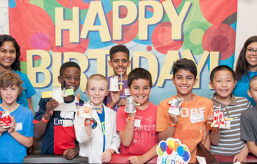 A group of children at a birthday party at the Science Centre along with two Science Centre staff.