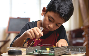 A boy works on a home electronics kit.