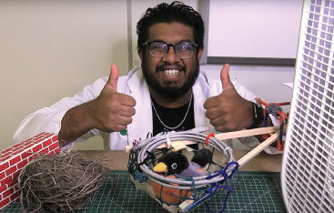 An educator gives the thumbs up while displaying his constructed bird nest.