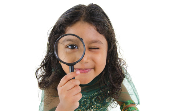 Young child looks through a magnifying glass.