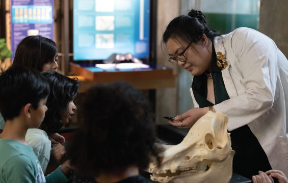 A host in a white lab coat shows different animals skulls to a group of children.