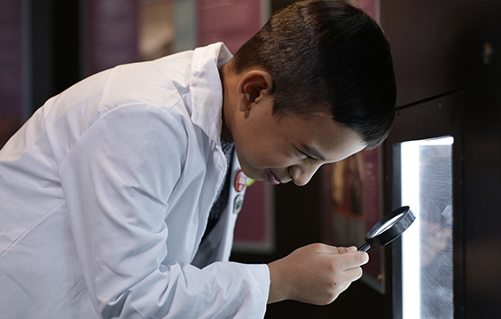 A boy examines an exhibit with a magnifying glass at the Science Centre.