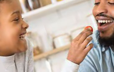 A child places a piece of food in an adult's mouth.