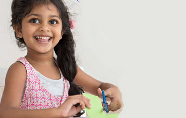 A young girl cutting paper with a pair of scissors.