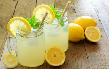 Glasses of lemonade surrounded by lemons.