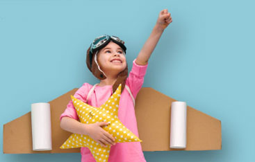 A girl wearing a homemade rocket pack holds her fist in the air.