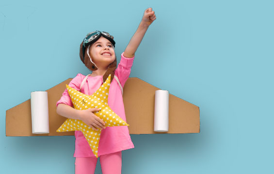A young girl poses with her fist in the air wearing a home made jet pack.