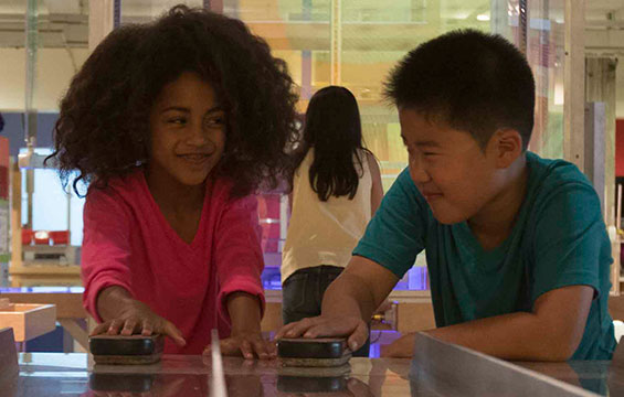 Two children experiment with friction in the Weston Family Innovation Centre.