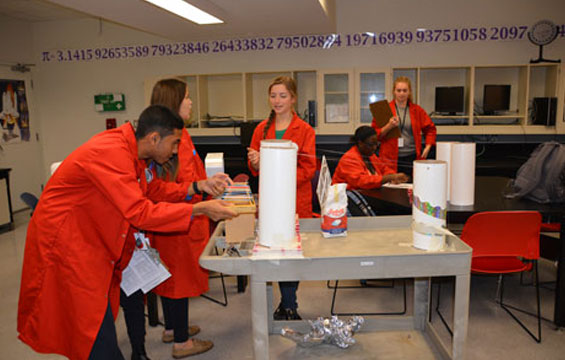 Science School students work on a project in their red lab coats.