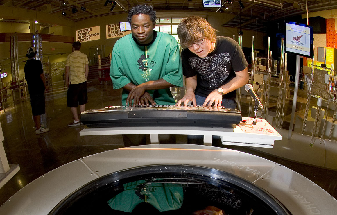 Two teens play with ferrofluid triggered by a keyboard.