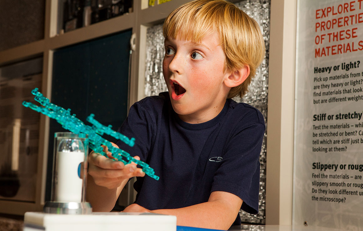 A young boy reacts in amazement as he creates something new.