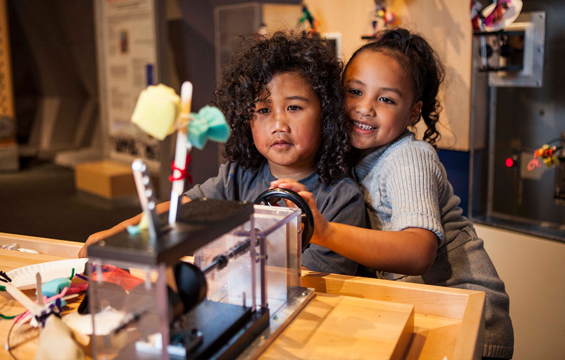 Two young children play with a kintetic sculpture.