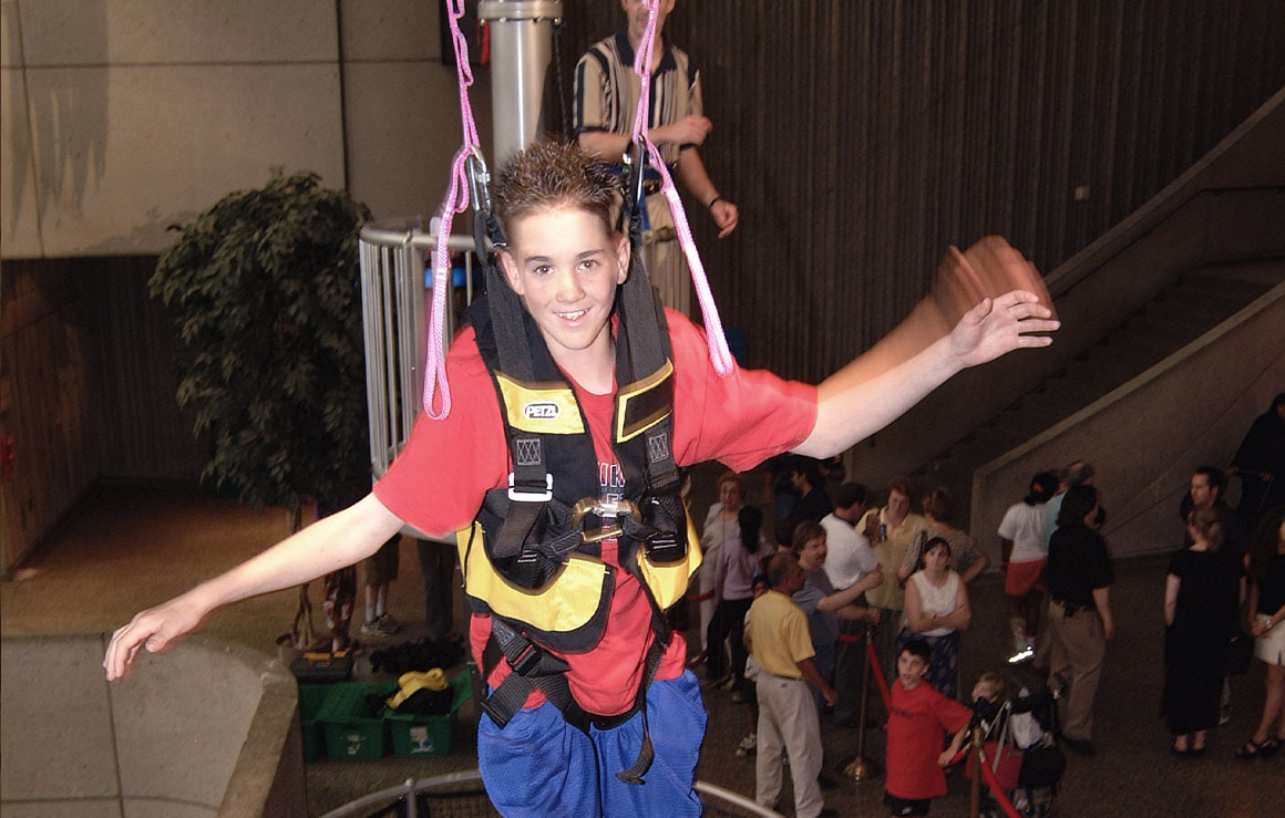 A person in a harness tries out the high wire exhibit.