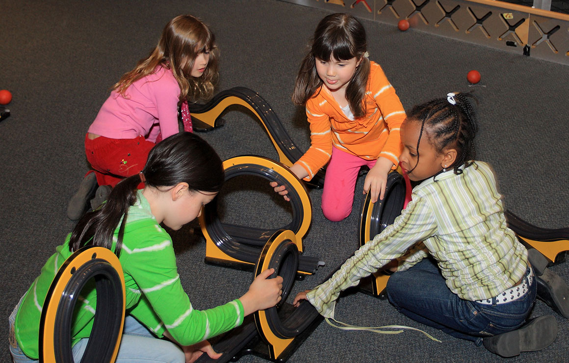 Four children assemble coaster tracks.