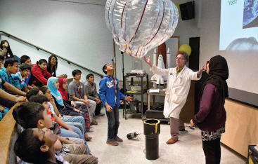 A class of students watches a Science Centre educator demonstrate with a large balloon.