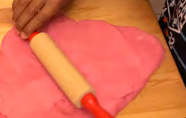 A child rolls out homemade play dough.