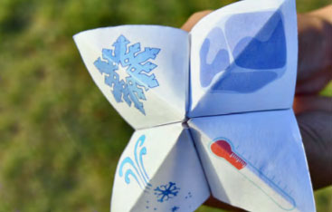 A hand folded paper toy with drawing of snow on it.