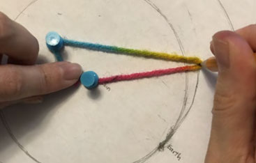 A close up of fingers, wool and thumbtacks.