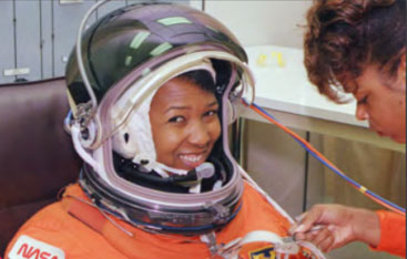 A woman helps an astronaut suit up.