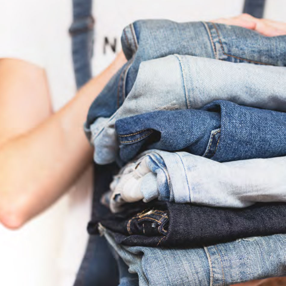 A person stacking a pile of jeans.