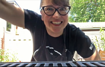 A woman opening up a barbecue.