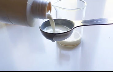 Sunscreen pours from a bottle into a spoon.