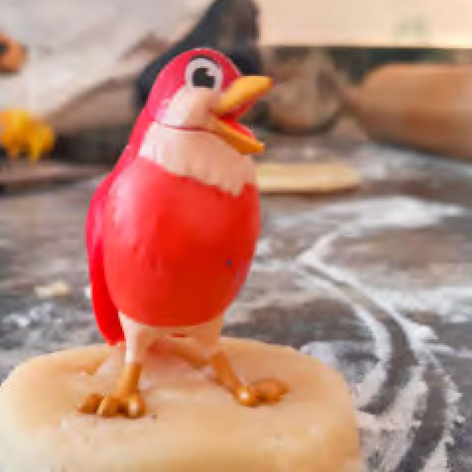 A toy bird being used to make tracks in cookie dough.