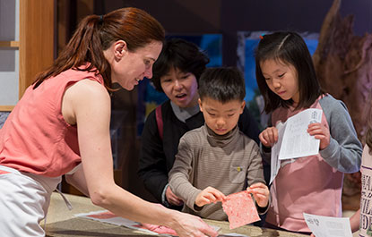 A woman demonstrates papermaking to visitors.