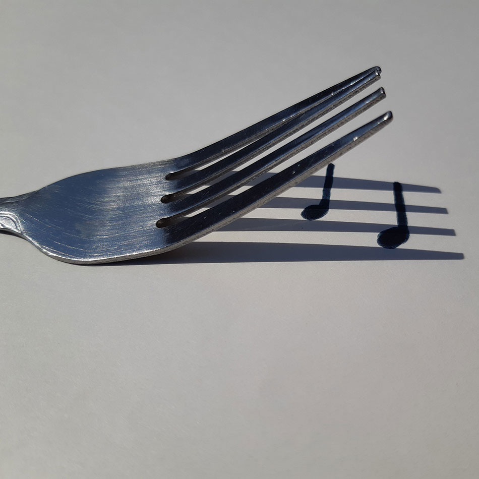 A fork casting a shadow with music notes drawn on it.