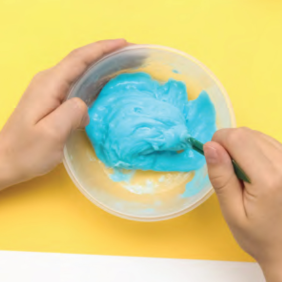 A close-up of hands mixing up blue slime in a plastic bowl.