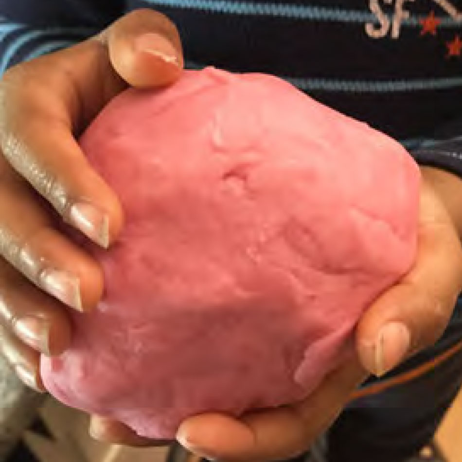 A child holds a bowl of homemade playdough.