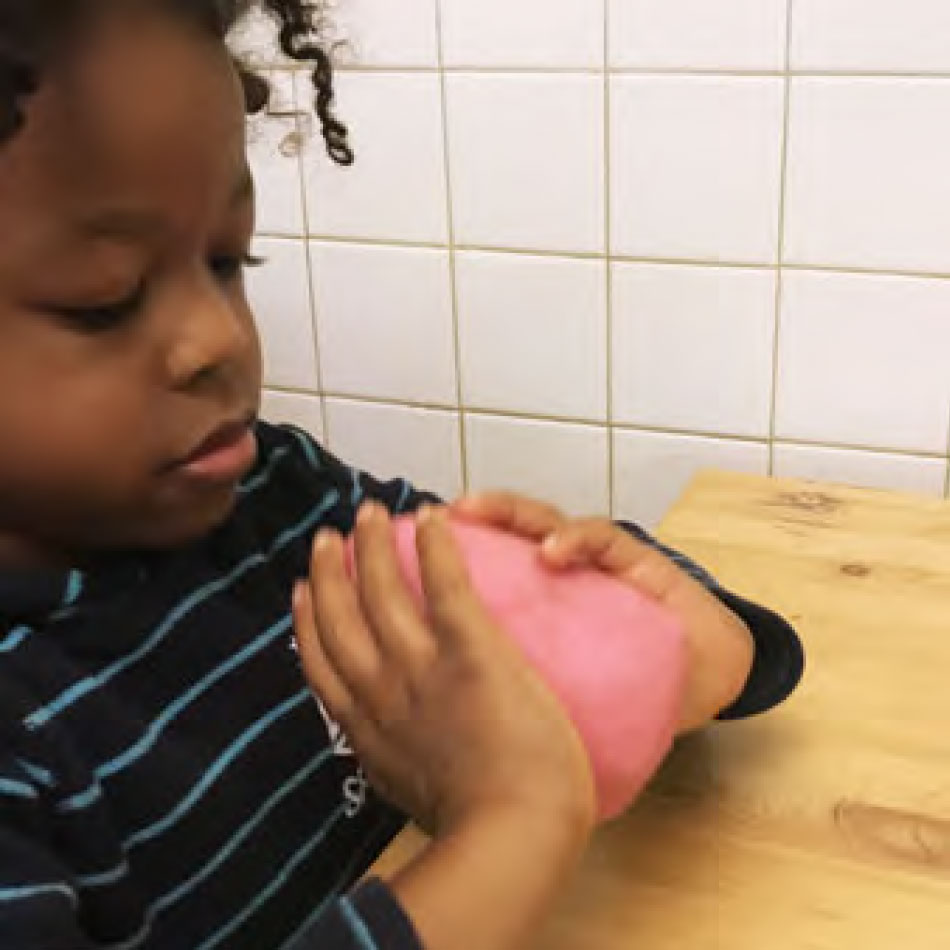 A child holds a ball of homemade playdough.