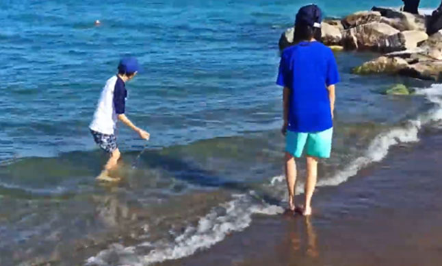 Two children play in waves.