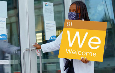 A science centre host holds a sign reading welcome.