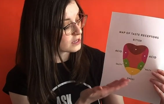 A Science Centre host holding up a paper with a map of the tongue on it.