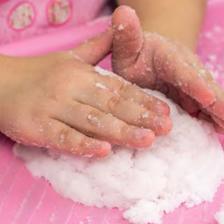 A close up of hands pressing down homemade snow.