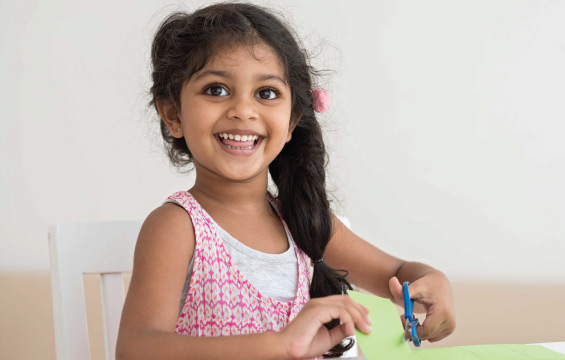 A young child cuts paper with scissors.