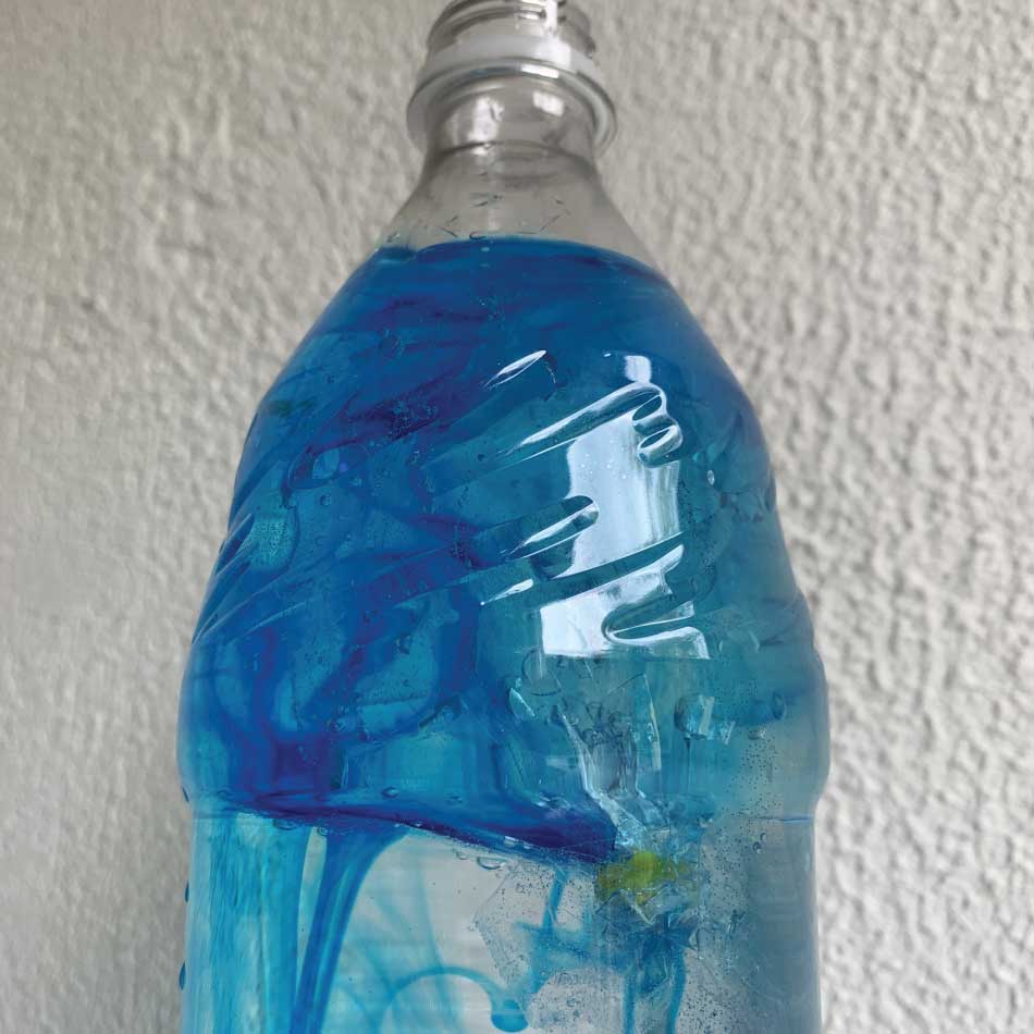 A plastic bottle containing water, a plastic bag and blue food colouring.