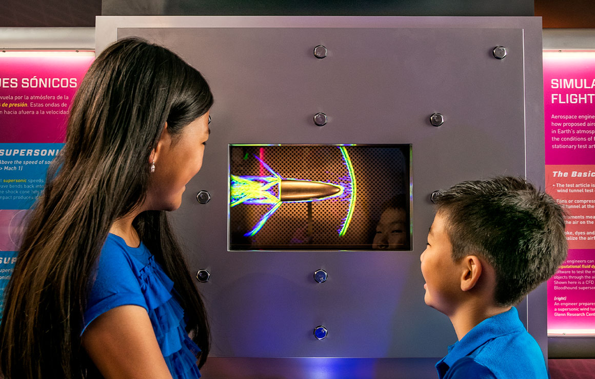 A boy and girl learning from an exhibit in Above and Beyond.