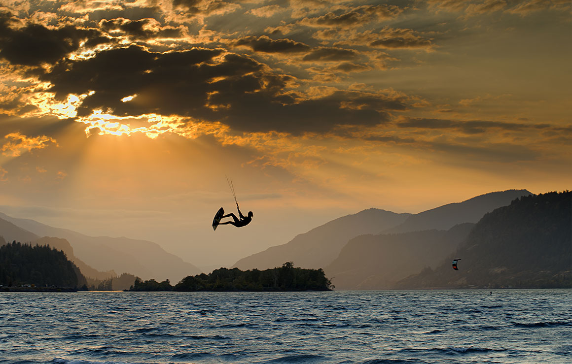 A person surfing under a sunset.