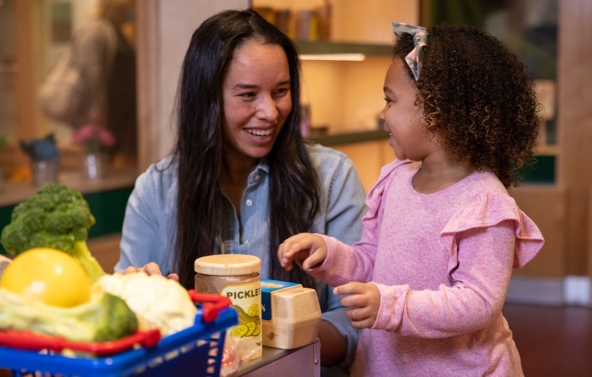 A woman and a girl playing with toy food.