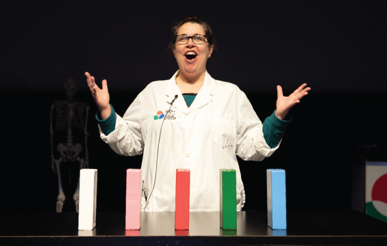 An educator presents a demonstration using 5 coloured blocks sitting on a table.