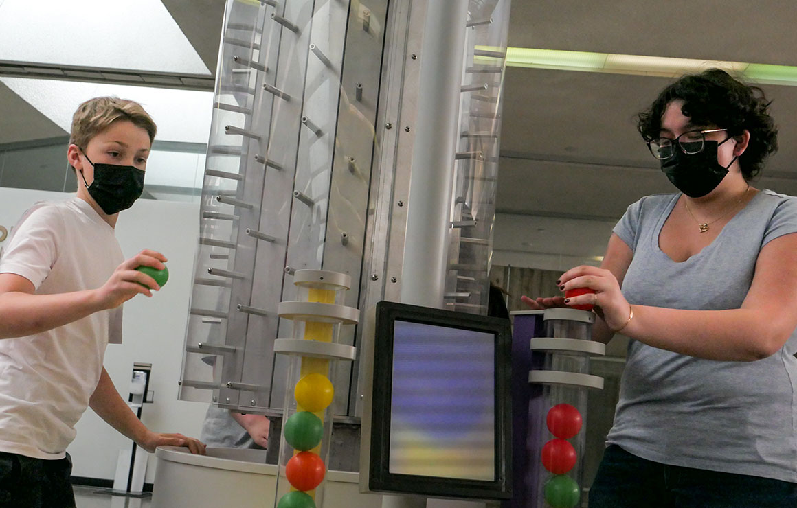 People placing balls in tubes in the exhibition.