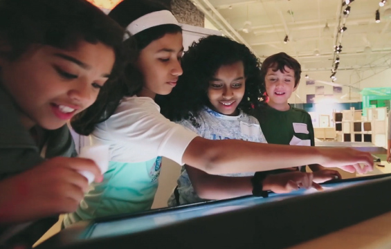 Four students interact with a touchscreen