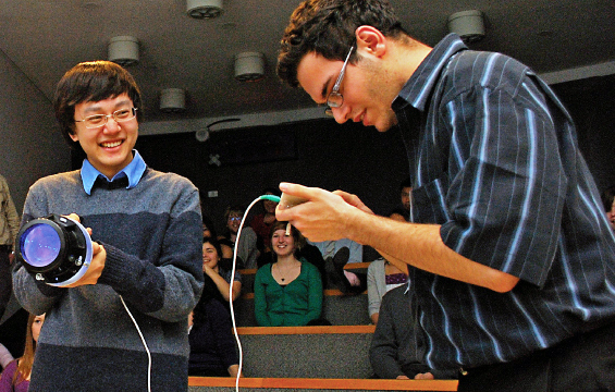 Two students make adjustments on a mechanical device.