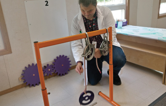 An educator adjusts a pulley lifting a weight
