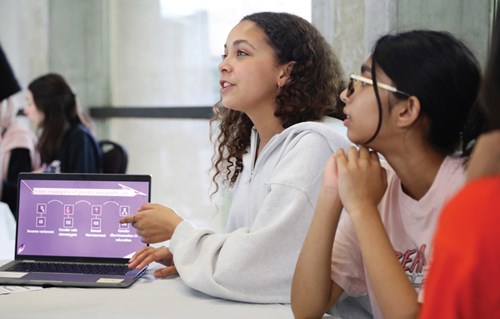 Two students present their project on a laptop.