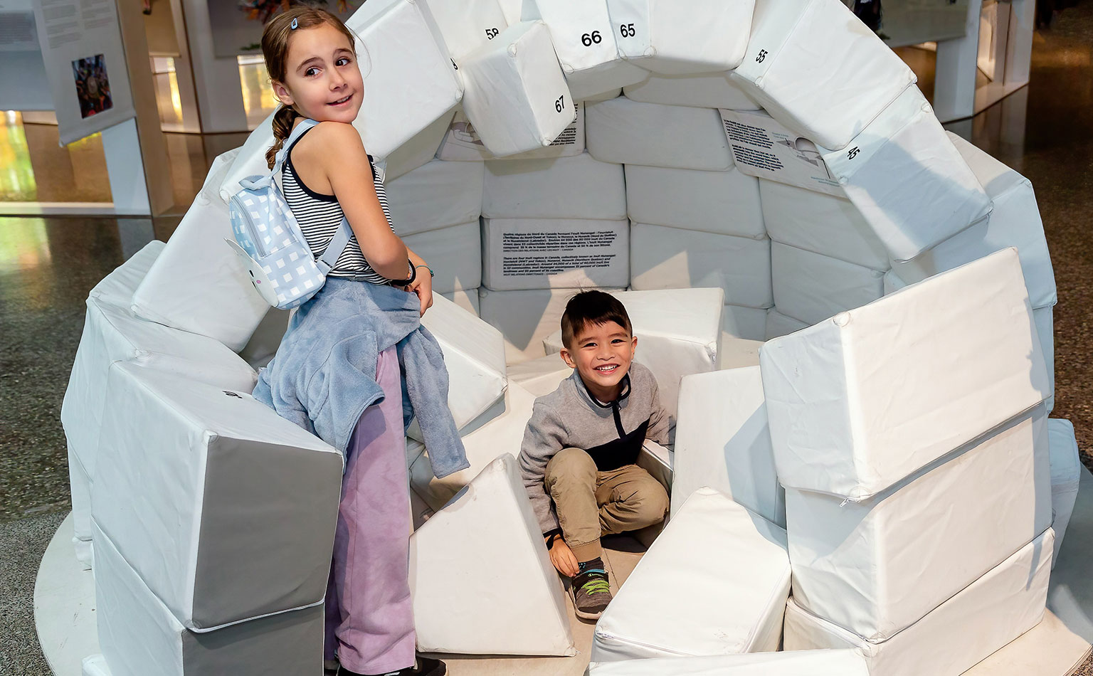 Two children learn to make a life-sized igloo.