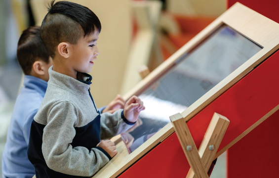 Two children interact with a touch screen.