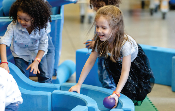 Two children play will a ball on the Imagination Station playset.